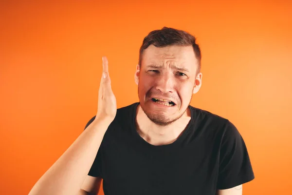 Man getting slapped on orange backgroundUnhappy scared man getting slapped standing on orange background