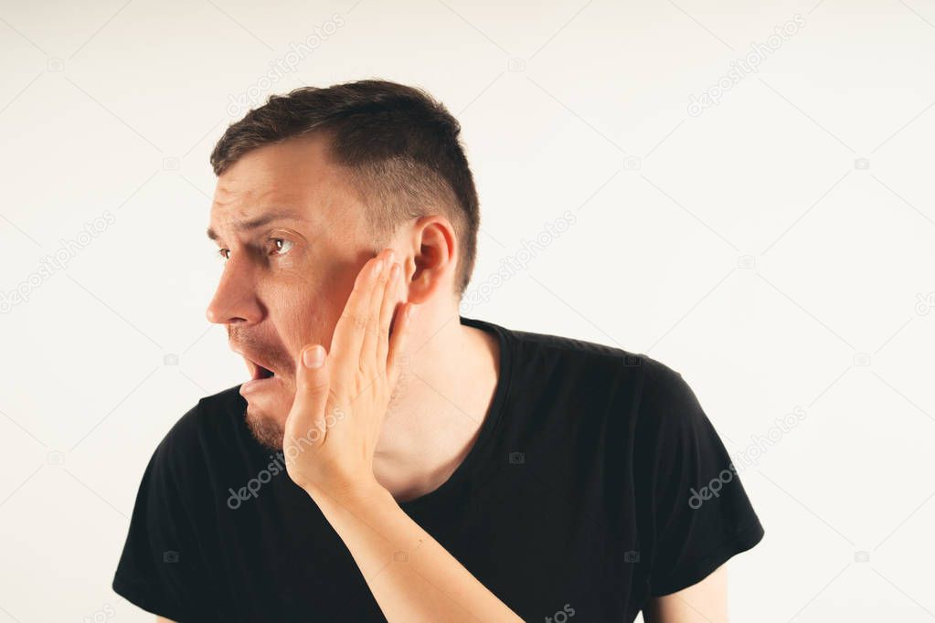 Crop person slapping scared man in faceEmotional male getting slapped in face while shouting with closed eyes in fear on white background