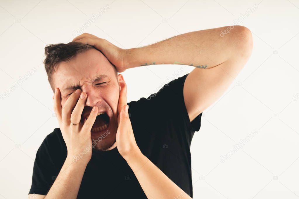Crop person slapping scared man in faceEmotional male getting slapped in face while shouting with closed eyes in fear on white background