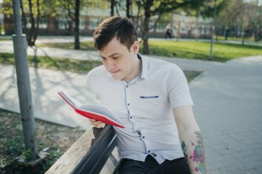 Park yerinde kırmızı defterli bir adam var.