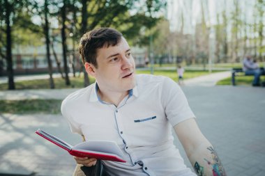 Park yerinde kırmızı defterli bir adam var.