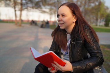 Kadınların elleri sokakta kırmızı bir defter tutuyor.