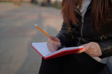 Caddeye kırmızı defterle notlar yazan bir kadın.