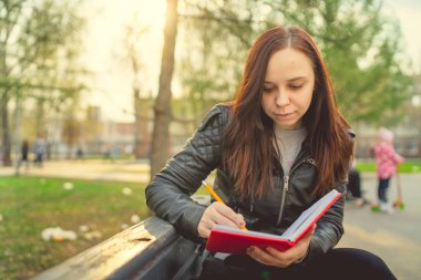 Caddeye kırmızı defterle notlar yazan bir kadın.