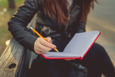 Caddeye kırmızı defterle notlar yazan bir kadın.