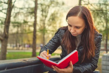 Caddeye kırmızı defterle notlar yazan bir kadın.