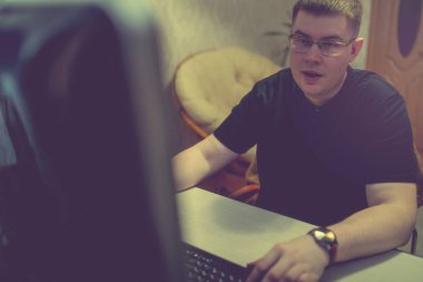 Bilgisayardaki genç adam, dizüstü bilgisayarda çalışıyor.