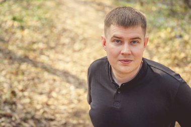 Bir adam sonbahar ormanında poz verir..