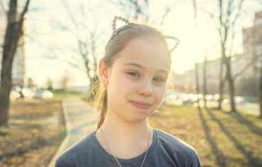 Sıradan giyinmiş bir kızın portresi çocuk parkında duruyor.