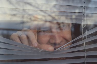 Pencereden bakan bir adam. Genç düşünceli erkek portresi. Kahverengi gözlü. Pencere kenarından bakan.