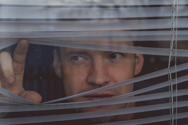 Pencereden bakan bir adam. Genç düşünceli erkek portresi. Kahverengi gözlü. Pencere kenarından bakan.