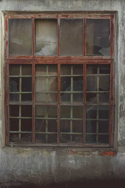 Window with broken glass in old buildingWooden window frame with partially broken glass in old abandoned brick building