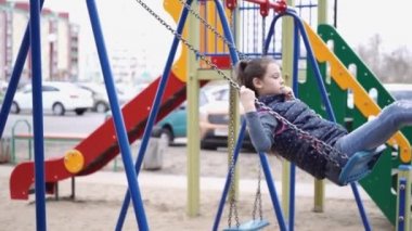 Salıncakta günlük giysiler içinde bir kızın portresi.
