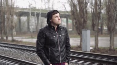 Tren istasyonundaki adam demiryolunun arkasında.