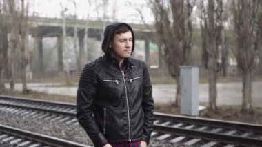 Tren istasyonundaki adam demiryolunun arkasında.