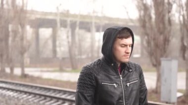 Tren istasyonundaki adam demiryolunun arkasında.