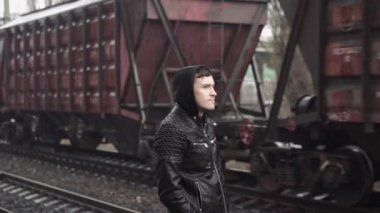 Tren istasyonundaki adam demiryolunun arkasında.