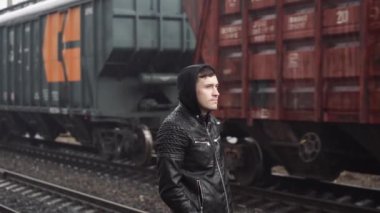 Tren istasyonundaki adam demiryolunun arkasında.