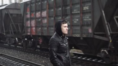 Tren istasyonundaki adam demiryolunun arkasında.