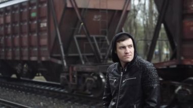 Tren istasyonundaki adam demiryolunun arkasında.