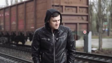 Tren istasyonundaki adam demiryolunun arkasında.