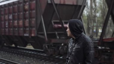 Tren istasyonundaki adam demiryolunun arkasında.