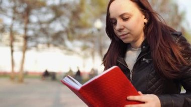 Sokakta kırmızı defterli bir kadın.