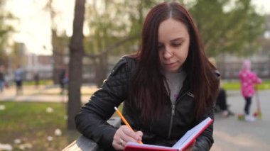 Caddeye kırmızı defterle notlar yazan bir kadın.