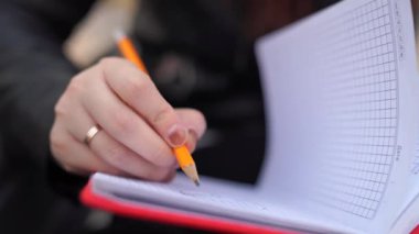 Caddeye kırmızı defterle notlar yazan bir kadın.