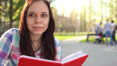 Sokakta elinde kırmızı bir defter tutan kadın.