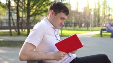 Adam parkta kitap okuyor.