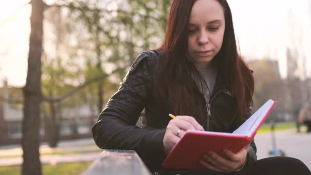 Femme qui écrit des notes dans un carnet rouge dans la rue