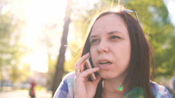 在春天的森林里用智能手机说话的年轻女人 — 图库视频影像