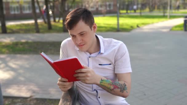 Άνθρωπος Που Διαβάζει Ένα Βιβλίο Στο Πάρκο — Αρχείο Βίντεο