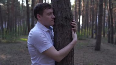 Sıradan kıyafetler içinde genç bir adamın portresi. Sarılma ağacı.