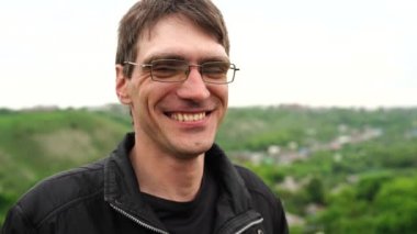 Kameraya bakan neşeli gülümseyen adam. Mutlu genç adam bir yaz günü parkta rahatlatıcı. Thoothy gülümseme ile kameraya bakarak rahat yakışıklı adam Portresi. Gülen adam