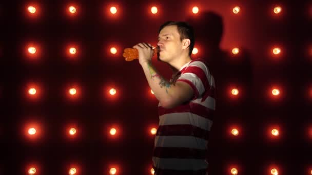 A man with a tattoo drinks a refreshing drink. Young caucasian male drinking a drink from the bottle — Stock Video
