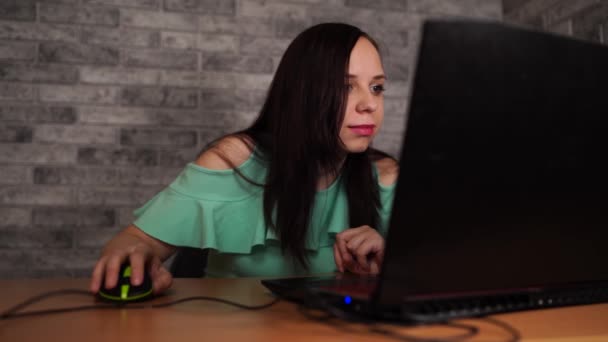 白いレンガの壁の背景、人と技術、ライフスタイル、教育、ビジネスコンセプトの前に座ってラップトップコンピュータを使用している若い女性 — ストック動画