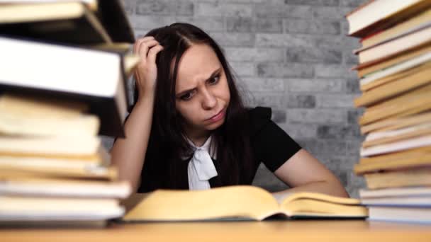 Kvinna elev tråkig läsbok på biblioteket med en massa böcker på universitetet. Student nedslagen läsbok för examination. — Stockvideo