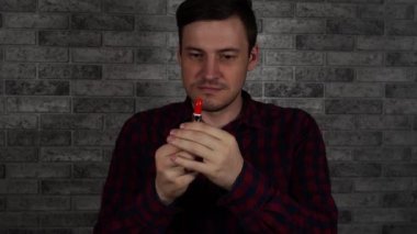 Bir adam kırmızı ruj ile dudaklarını boyar, bir tuğla duvara karşı