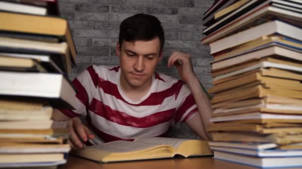 Man student saai boek lezen in de bibliotheek met veel boeken in de Universiteit. Student ontmoedigd lezen boek voor onderzoek. — Stockvideo