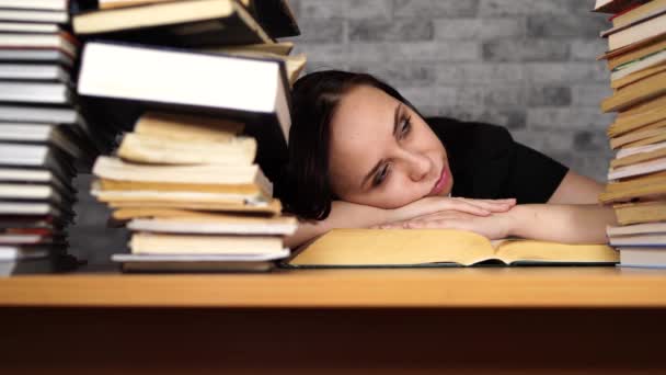 Beautiful woman student studying with a lot of paper books on the table — Stock Video