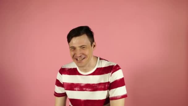 분홍색 배경에 서 있는 웃 고 웃는 티셔츠의 젊은 남자 — 비디오