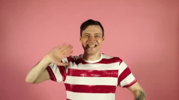 O homem acenou com a mão e sorriu em um fundo rosa — Vídeo de Stock