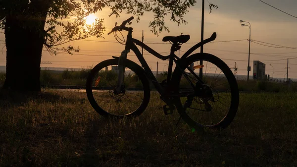 Beautiful close up scene of bicycle at sunset, sun on blue sky with vintage colors, silhouette of bike forward to sun. — Stock Photo, Image