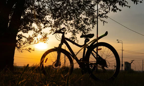 Bela cena de close up de bicicleta ao pôr do sol, sol no céu azul com cores vintage, silhueta de bicicleta para frente ao sol . — Fotografia de Stock