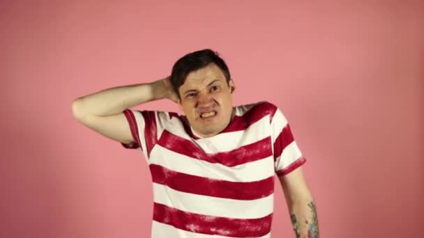 Frustrated man 30s on camera and scratching his head in bewilderment on pink background. Confused man scratching his head and shrugging — Stock Video