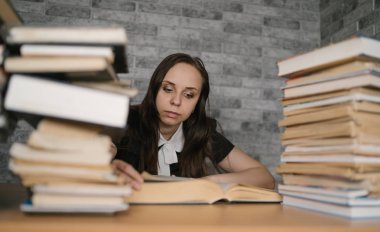 Üniversitede kitap bir sürü kütüphanede kadın öğrenci sıkıcı okuma kitabı. Muayene için öğrenci disheartened okuma kitabı.