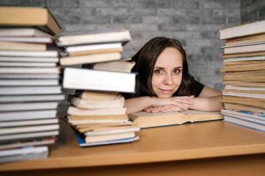 Masada bir sürü kağıt kitap ile okuyan güzel kadın öğrenci