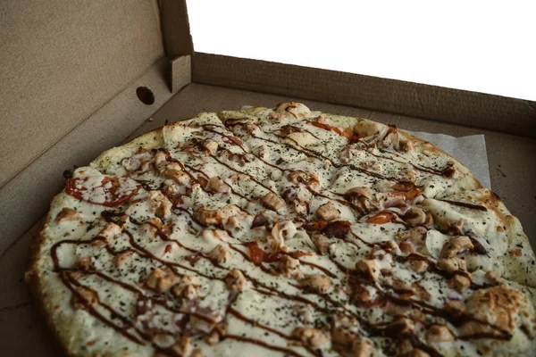 Gros plan de la pizza, dans une boîte en carton au-dessus de la table — Photo
